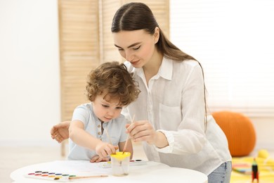 Photo of Mother and her little son painting with watercolor at home