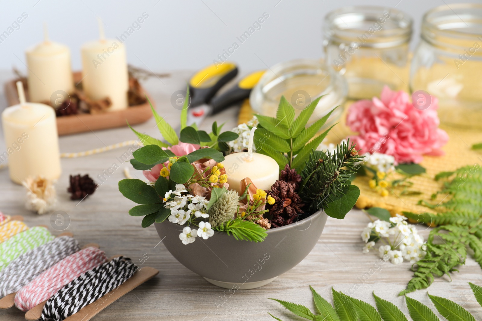 Photo of Beautiful floral composition with candle and different handicraft equipment on white wooden table. Master class in handmade craft