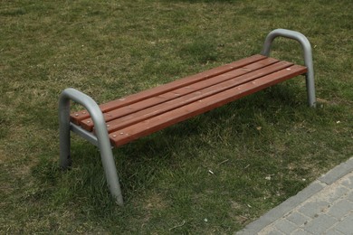 Photo of Modern wooden bench on green grass outdoors