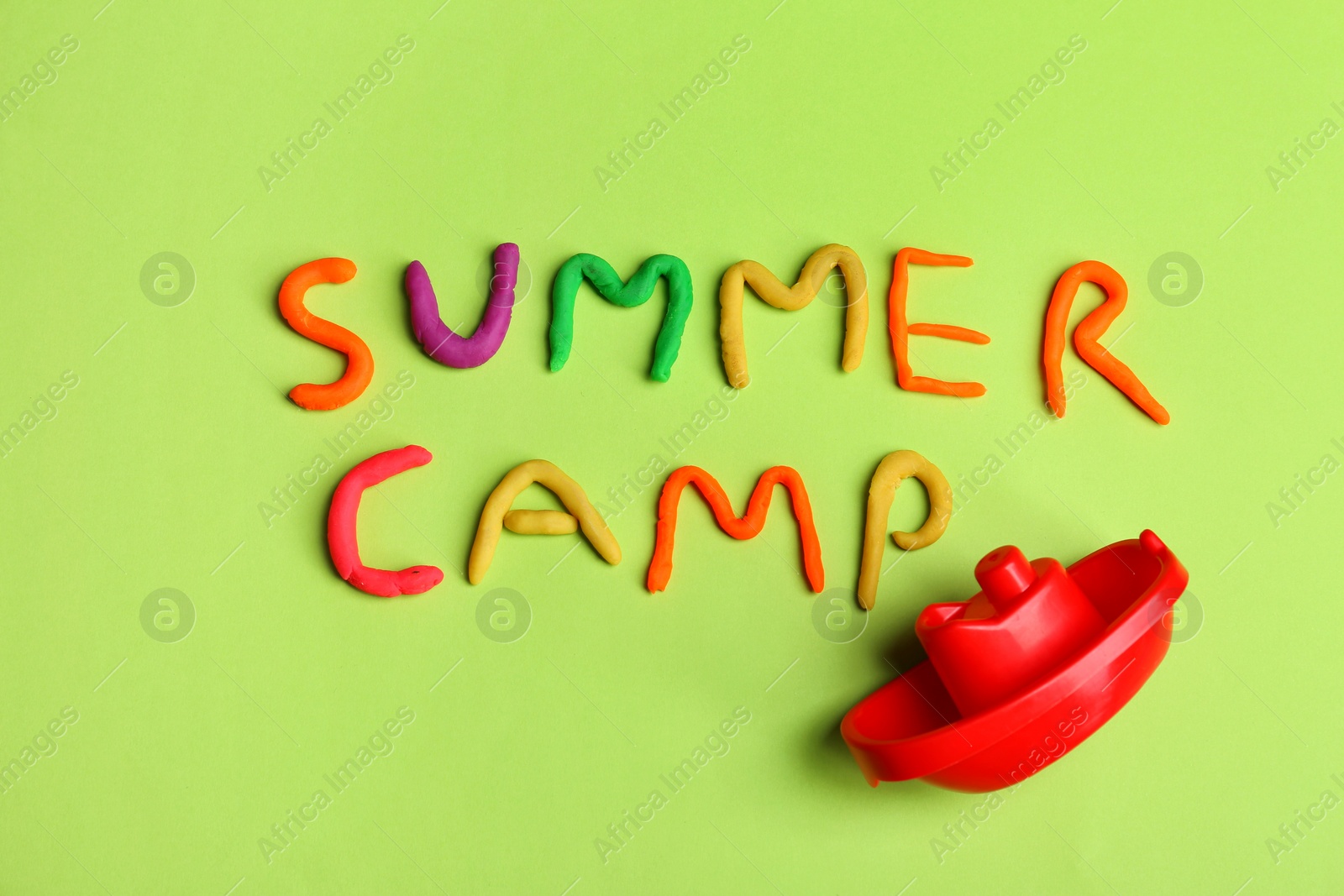 Photo of Words SUMMER CAMP made from modelling clay and plastic boat on color background, top view