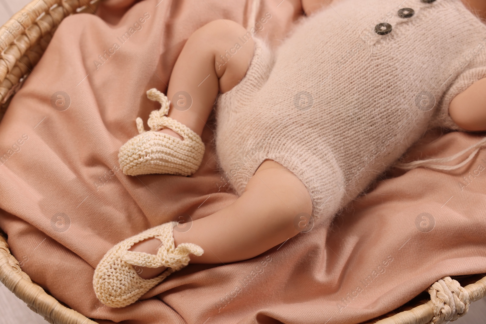 Photo of Newborn baby lying on blanket in wicker crib, closeup