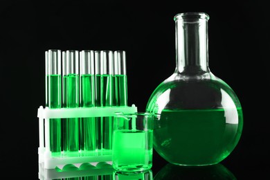 Laboratory glassware with green liquid on black background