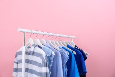 Photo of Rack with bright clothes on color background