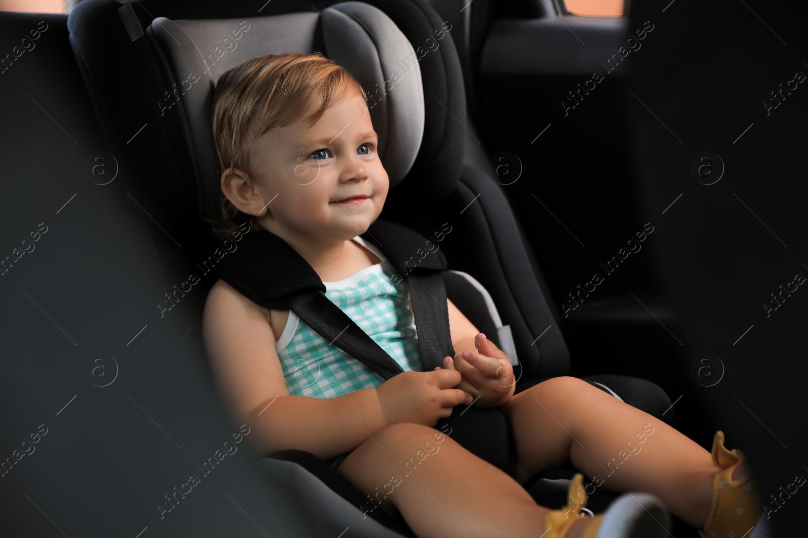 Photo of Cute little girl sitting in child safety seat inside car