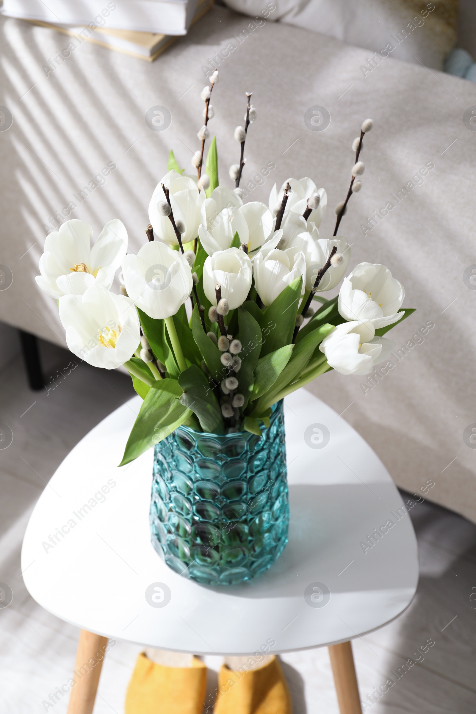 Photo of Beautiful bouquet of willow branches and tulips in vase on table indoors