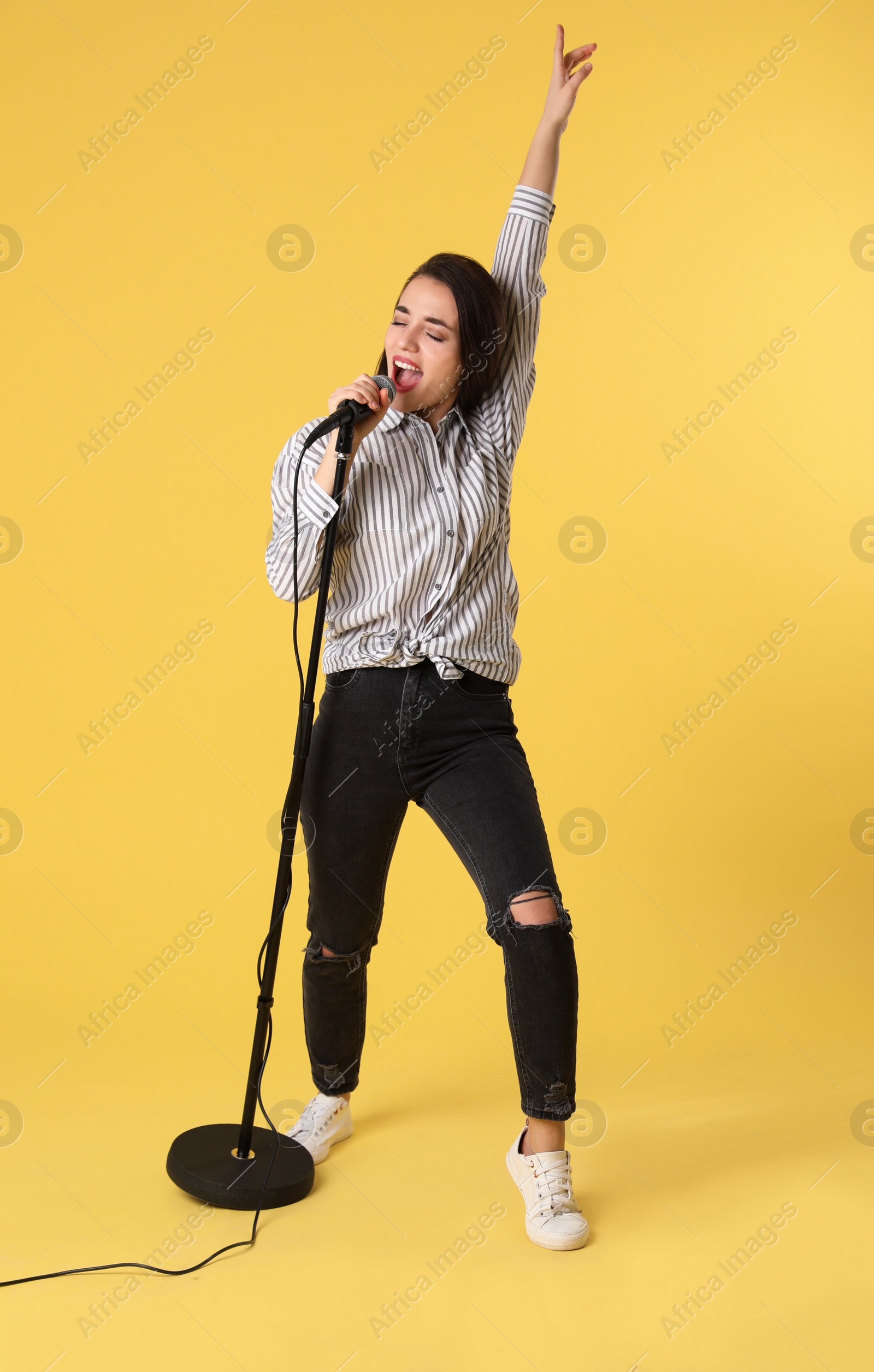 Photo of Young woman wearing casual clothes singing in microphone on color background