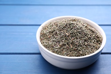 Photo of Bowl with dried thyme on blue wooden table, closeup