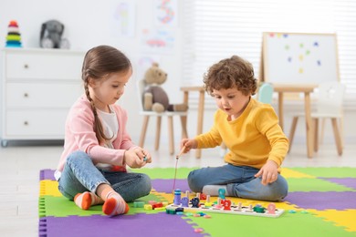 Cute little children playing with math game Fishing for Numbers on puzzle mat in kindergarten