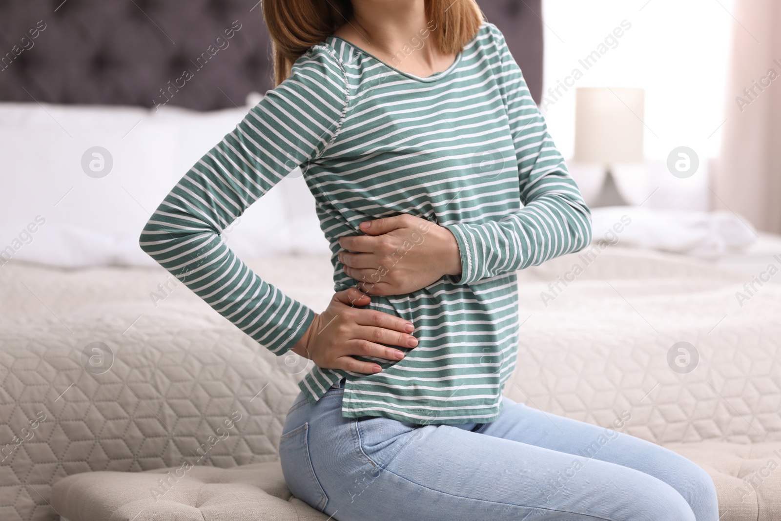 Photo of Young woman suffering from back pain at home, closeup