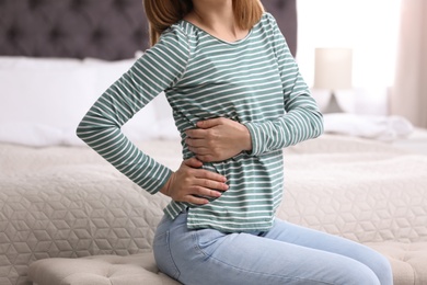 Young woman suffering from back pain at home, closeup