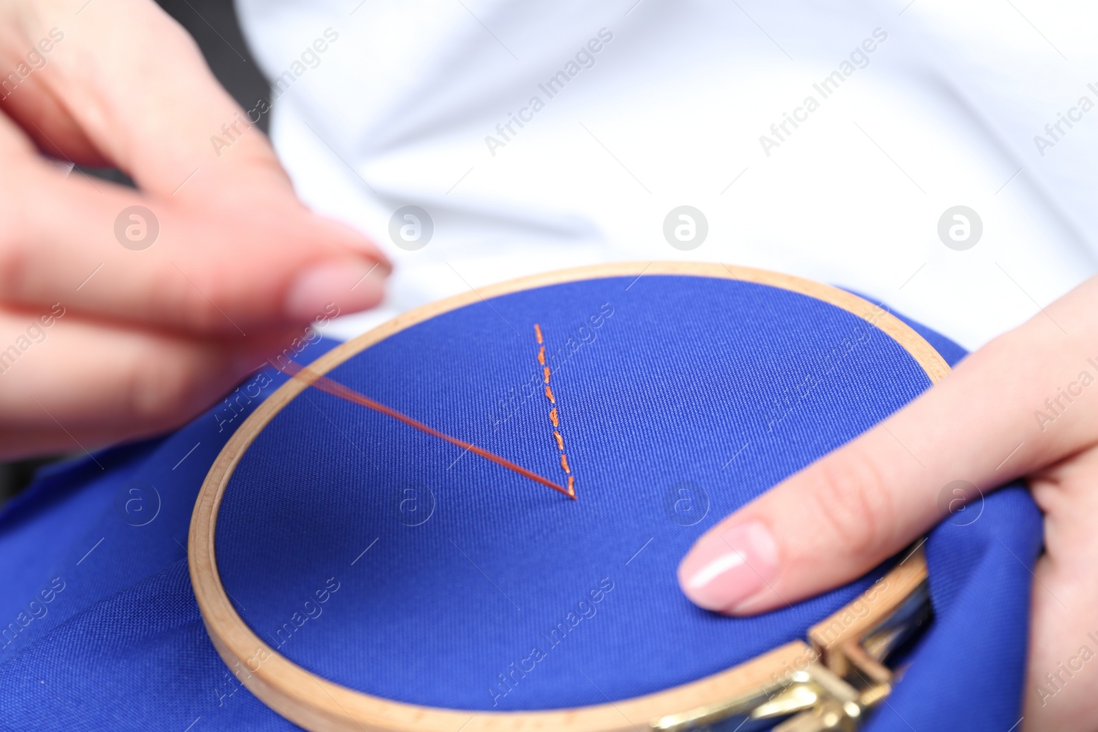 Photo of Woman with sewing needle and thread embroidering on cloth, closeup