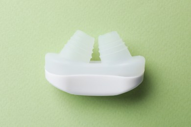 Photo of Anti-snoring device for nose on light green background, top view