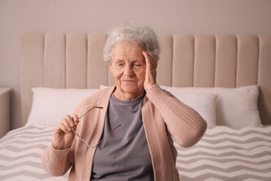 Senior woman with headache in bedroom at home