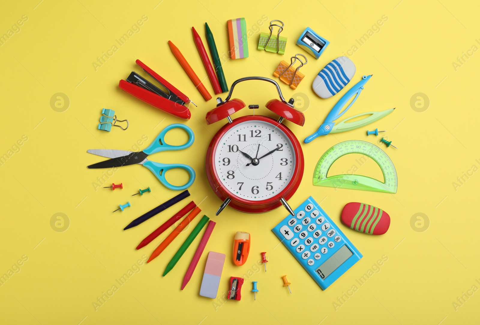 Photo of Flat lay composition with alarm clock and different stationery on yellow background. School time