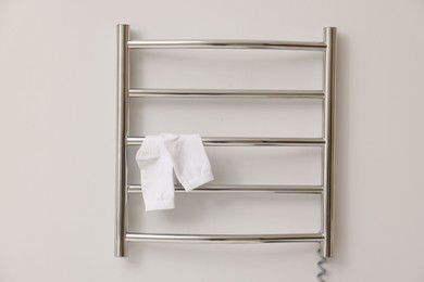 Photo of Heated towel rail with socks on white wall