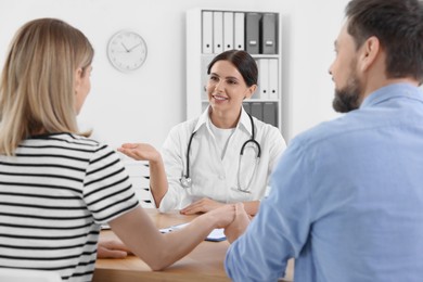 Photo of Couple having appointment with fertility doctor in clinic. Patient consultation