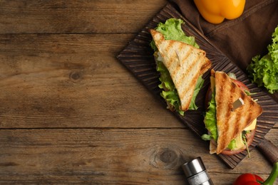 Photo of Wooden board with tasty sandwiches on table, flat lay. Space for text