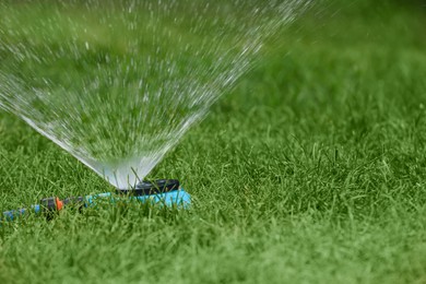 Photo of Automatic sprinkler watering green grass in park. Irrigation system