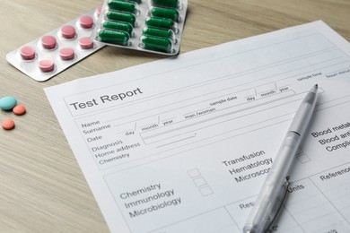 Photo of Drug test result form, pills and pen on wooden table, closeup