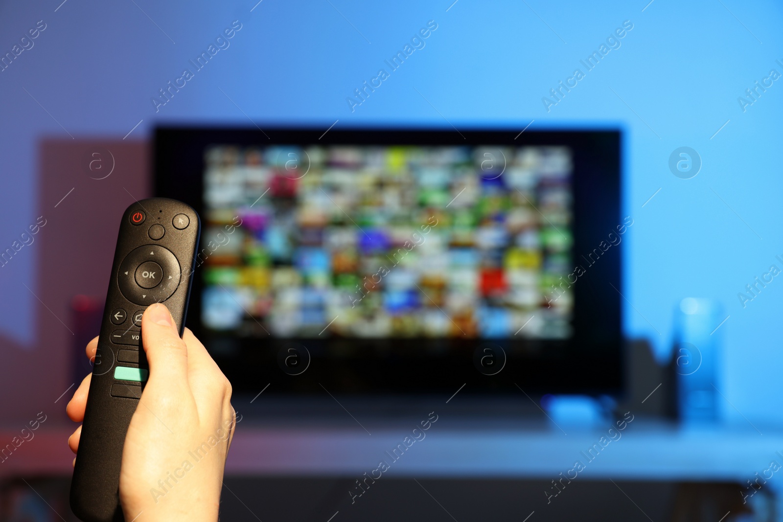 Photo of Woman switching channels on TV set with remote control at home, closeup. Space for text