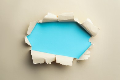 Hole in beige paper on light blue background
