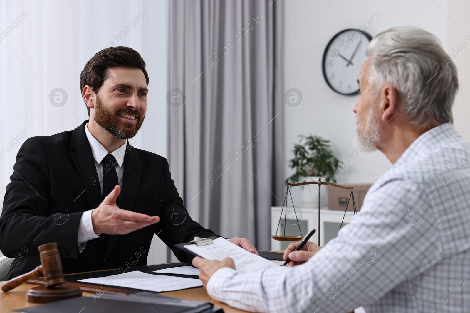 Photo of Senior man signing document in lawyer's office