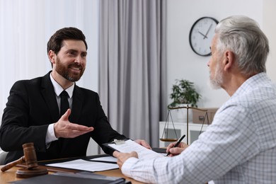 Photo of Senior man signing document in lawyer's office