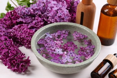 Lilac flowers and cosmetic products on white wooden table