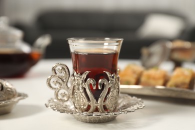 Photo of Cup of delicious Turkish tea served on white table, closeup