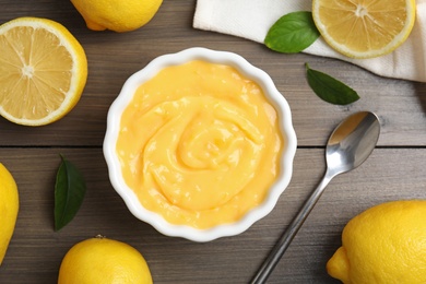 Photo of Delicious lemon curd in bowl on wooden table, flat lay