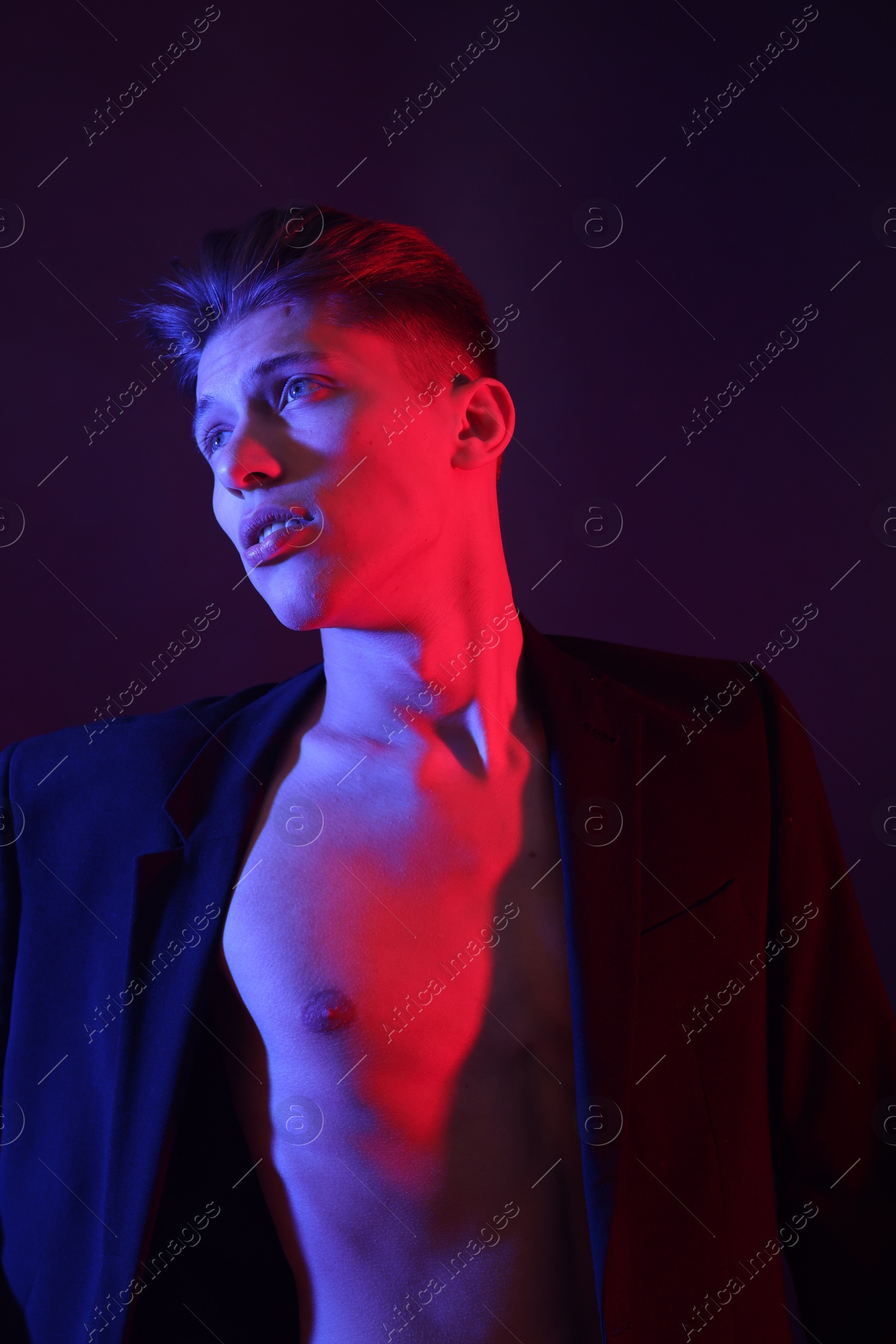 Photo of Sexy young man on dark background in neon lights