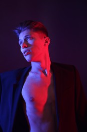 Photo of Sexy young man on dark background in neon lights