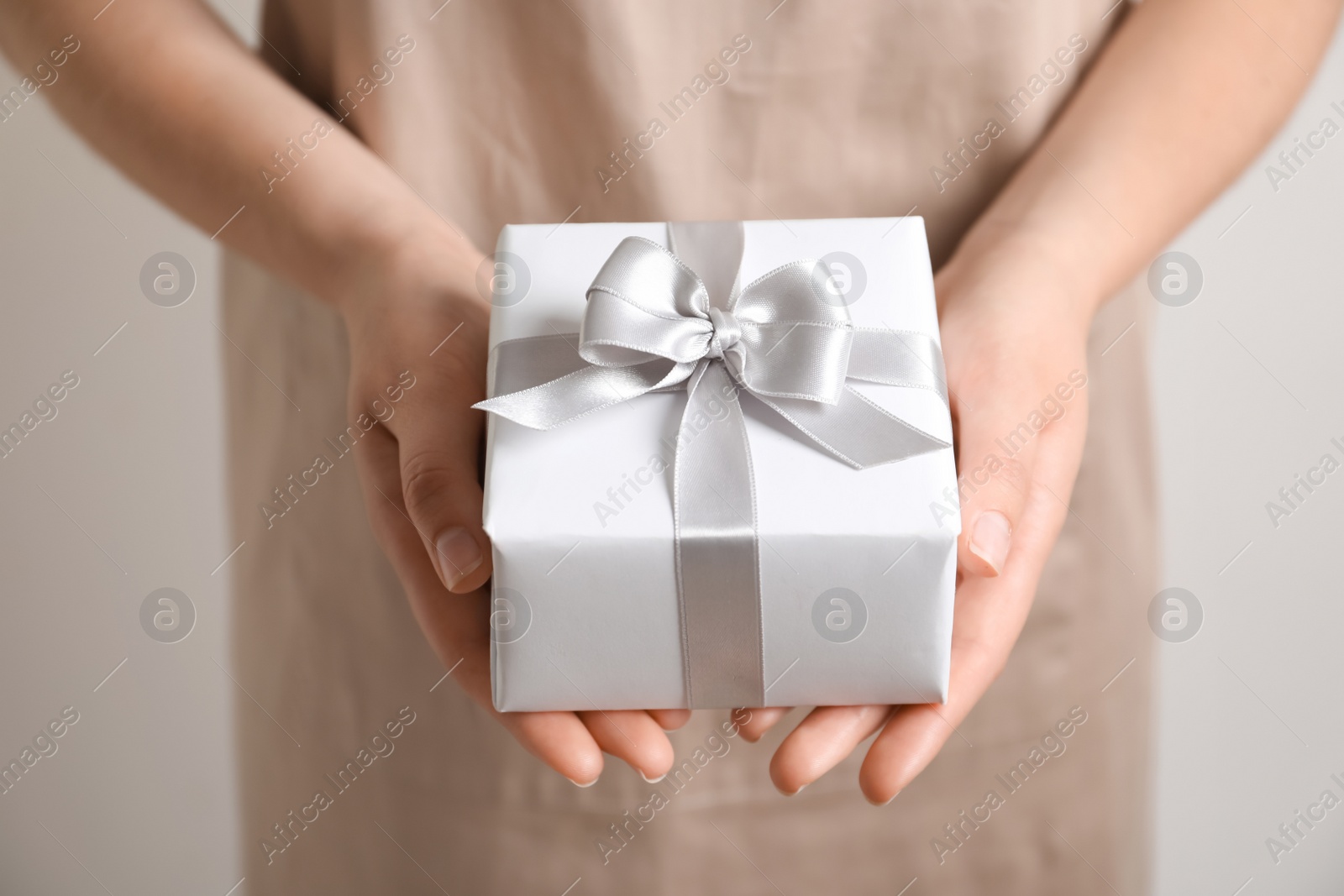 Photo of Woman holding gift box on light background