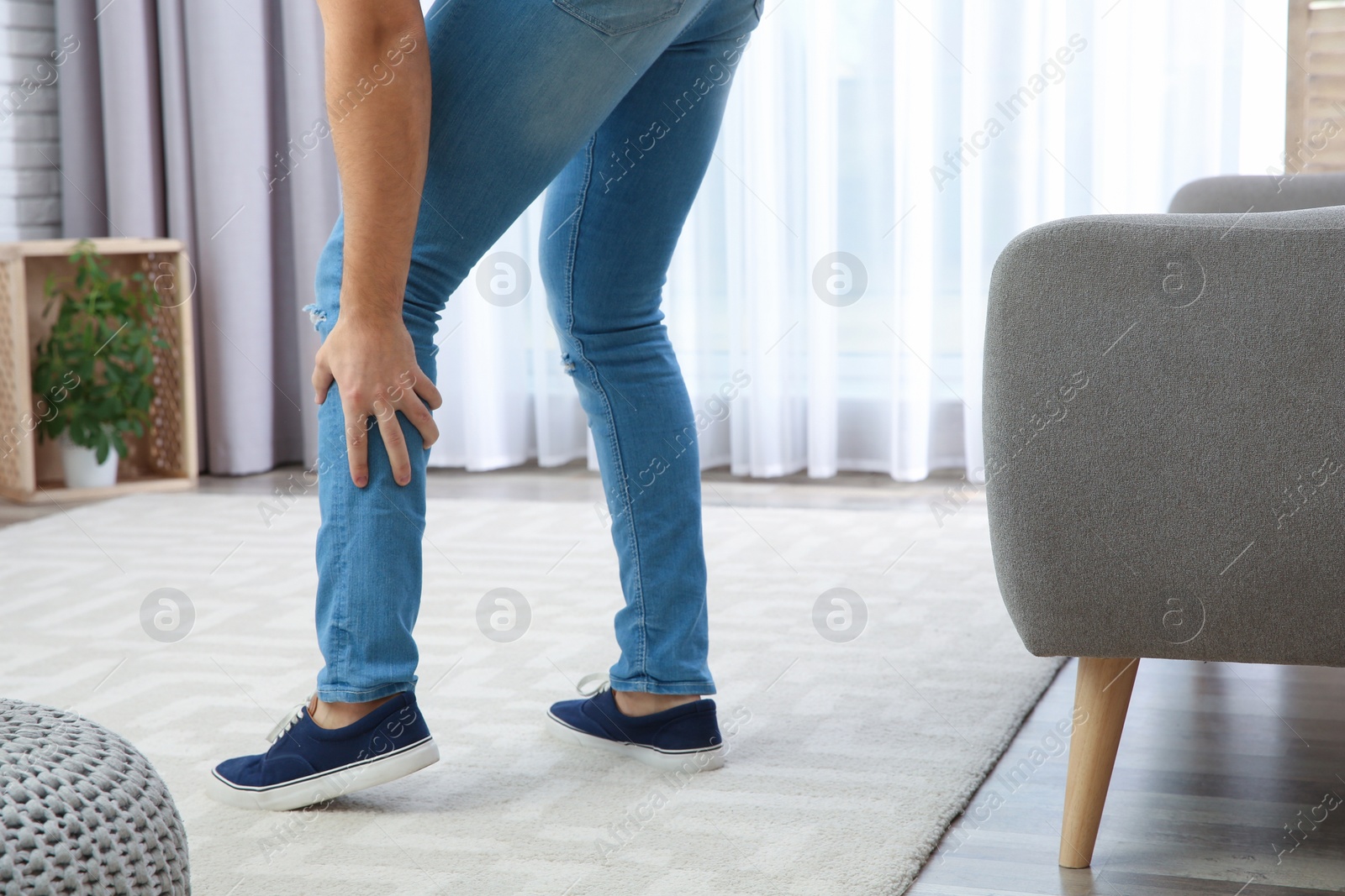 Photo of Man suffering from leg pain at home, closeup