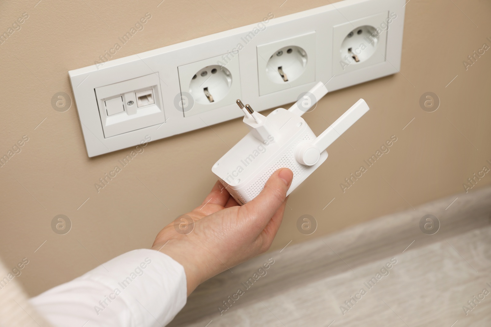 Photo of Woman holding wireless Wi-Fi repeater indoors, closeup