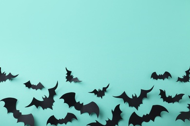 Many black paper bats on light blue background, flat lay with space for text. Halloween decor