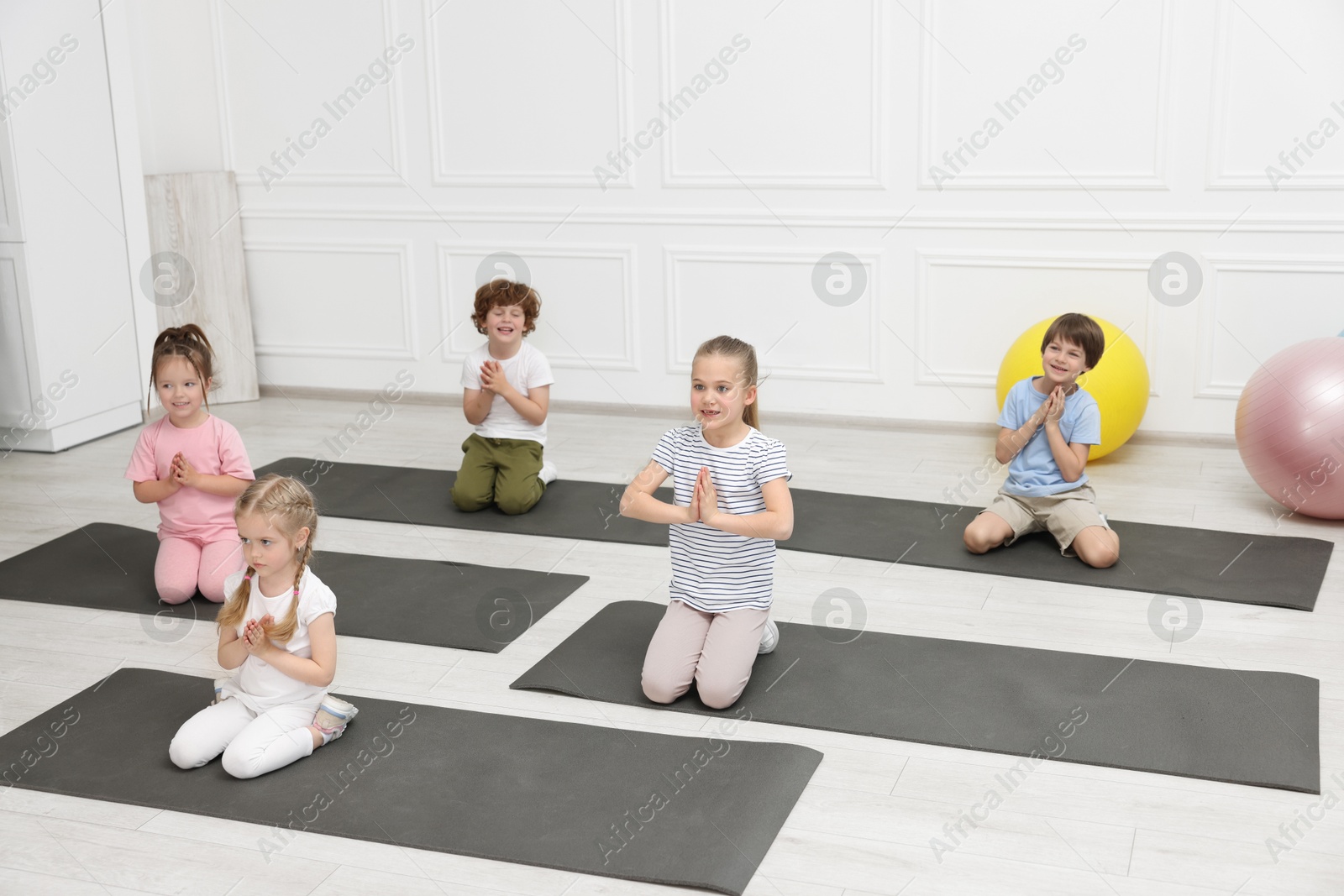 Photo of Group of children doing gymnastic exercises on mats indoors