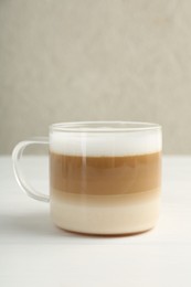 Aromatic coffee in glass cup on white wooden table