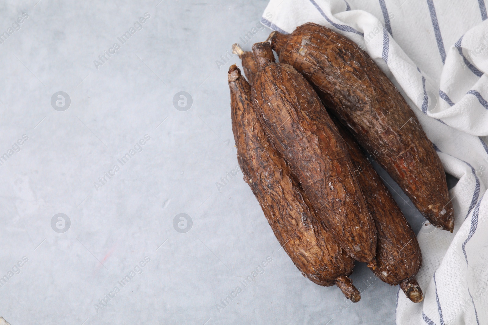 Photo of Fresh cassava roots on grey table, top view. Space for text