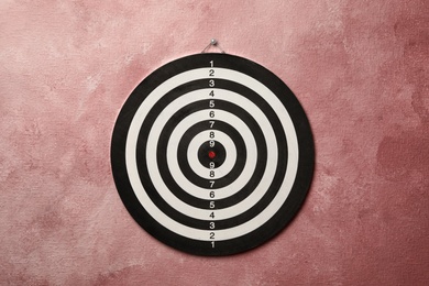 Photo of Dart board hanging on pink textured wall