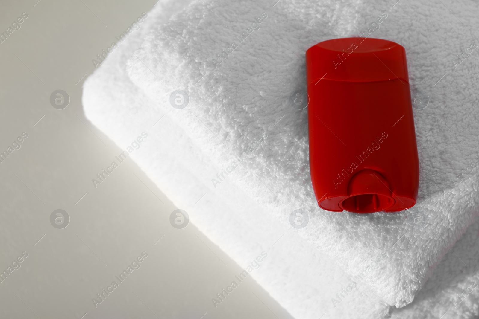 Photo of Deodorant with clean towels on light background, above view. Space for text