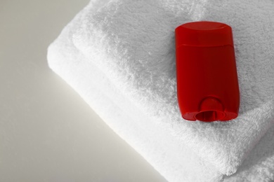 Photo of Deodorant with clean towels on light background, above view. Space for text