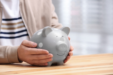 Photo of Man with piggy bank at wooden table, closeup