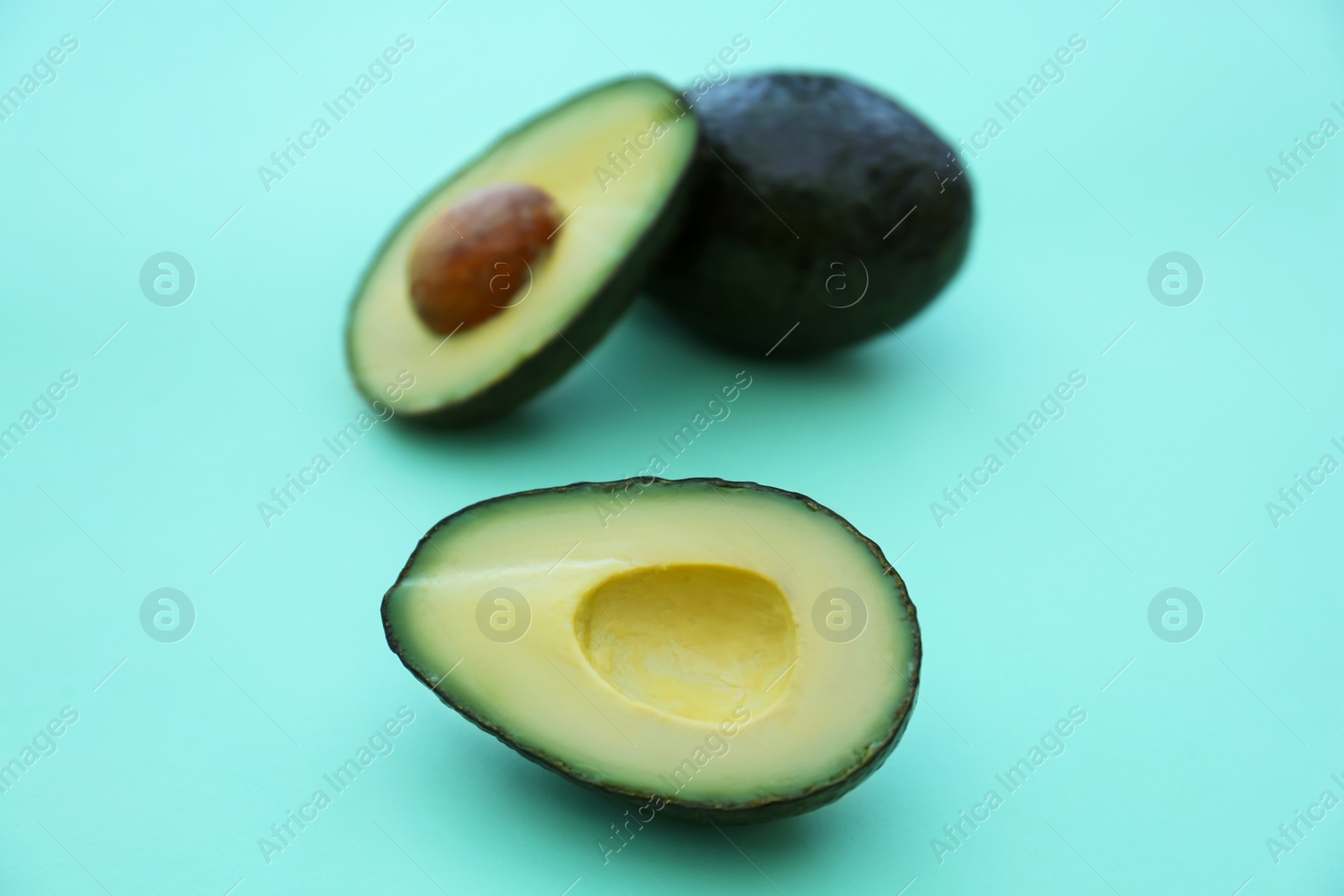 Photo of Tasty fresh ripe avocados on turquoise background