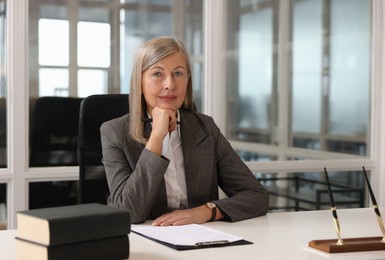 Photo of Smiling woman at table in office. Lawyer, businesswoman, accountant or manager