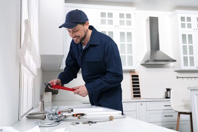 Professional plumber fixing water tap in kitchen