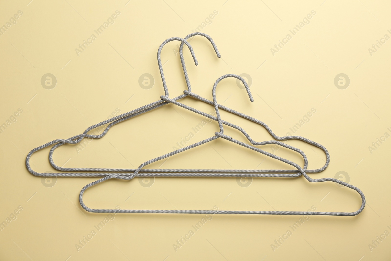 Photo of Hangers on pale yellow background, flat lay