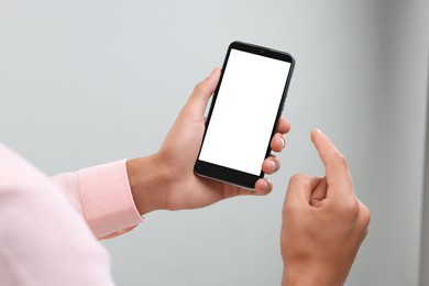Photo of Man using smartphone with blank screen on light grey background, closeup. Mockup for design
