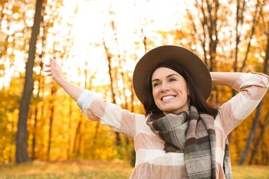 Photo of Beautiful woman wearing hat and scarf in sunny park. Autumn walk