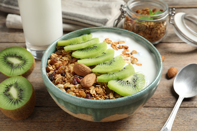 Image of Tasty granola with yogurt and sliced kiwi for breakfast on wooden table